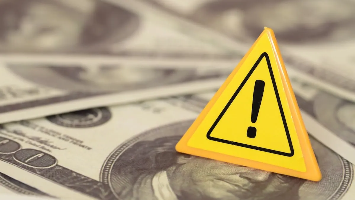 Warning symbol above US dollar banknotes